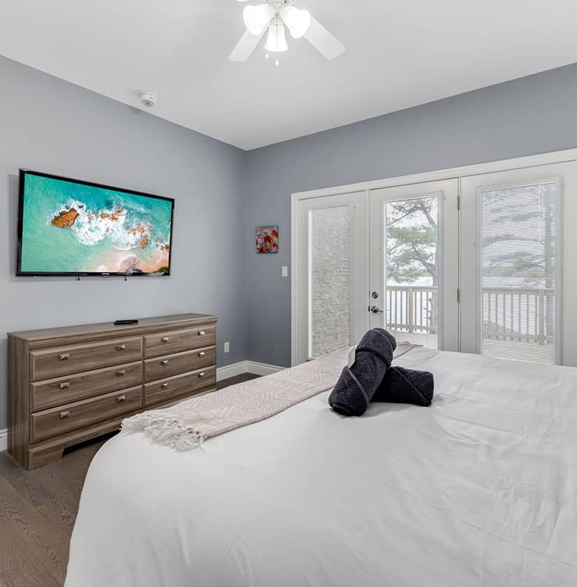 white bed with towels on it and a grey room with bay doors